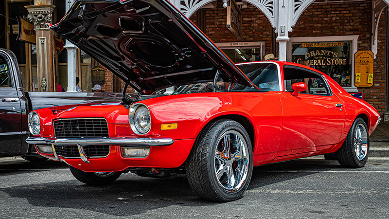 A wide angle shot of a red 1972 Chevy Camaro with its hood open