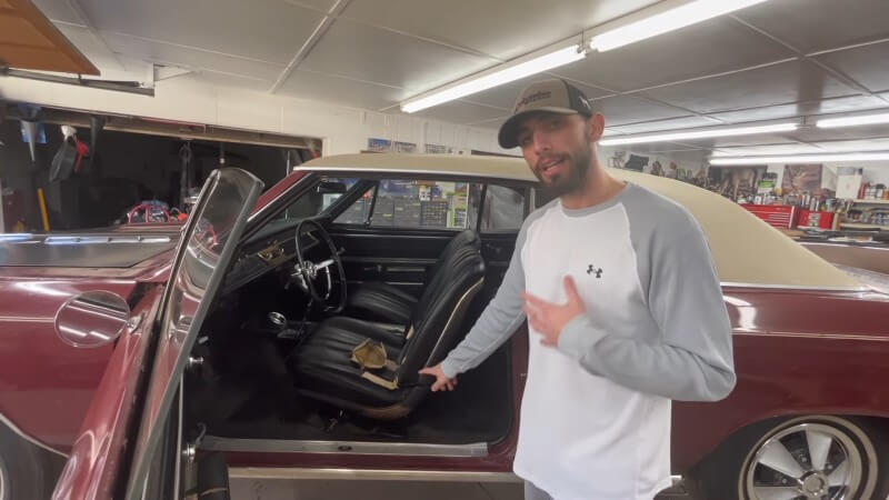 A mechanic pointing at black leather bucket seats in a 1966 Chevelle Super Sport