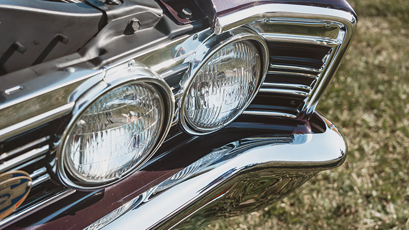 The front end of a burgundy 1967 Chevy Chevelle with a focus on the headlights and grille